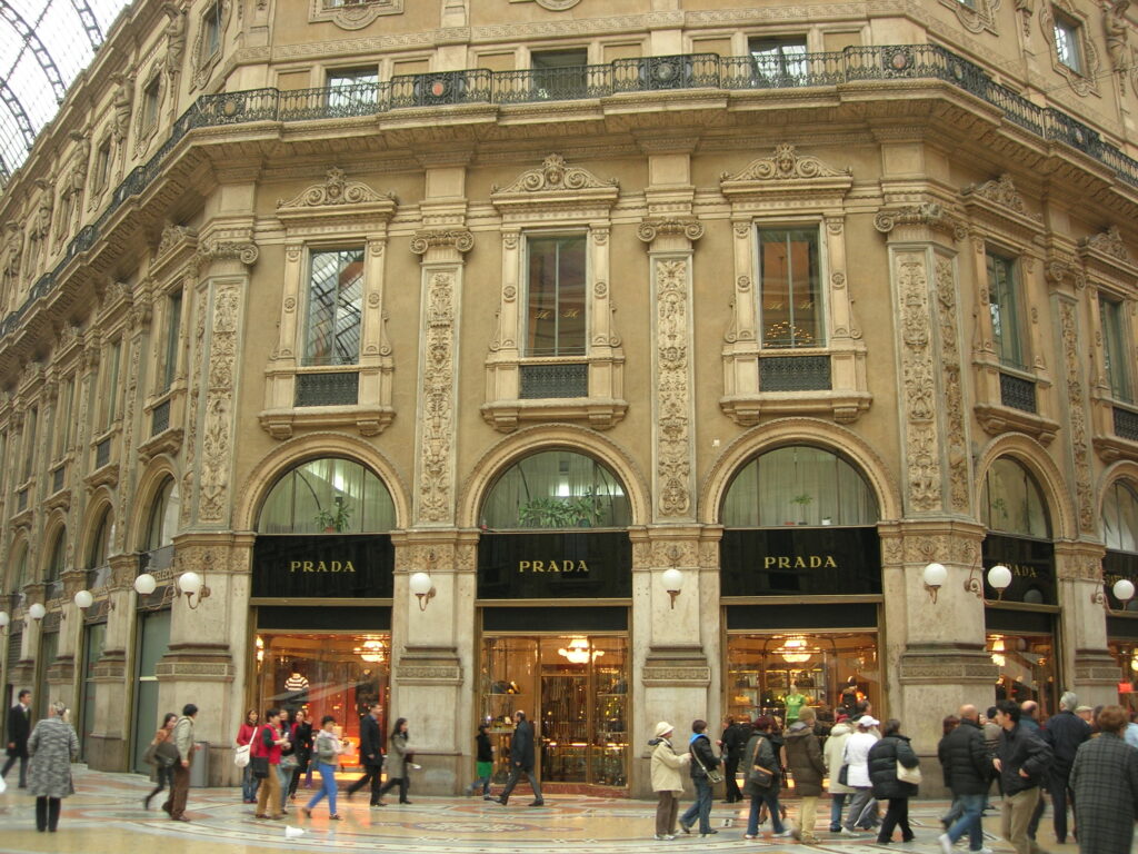Exterior of Prada store in Galleria Vittorio Emanuele II with shoppers walking by in Milan