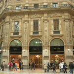 Exterior of Prada store in Galleria Vittorio Emanuele II with shoppers walking by in Milan