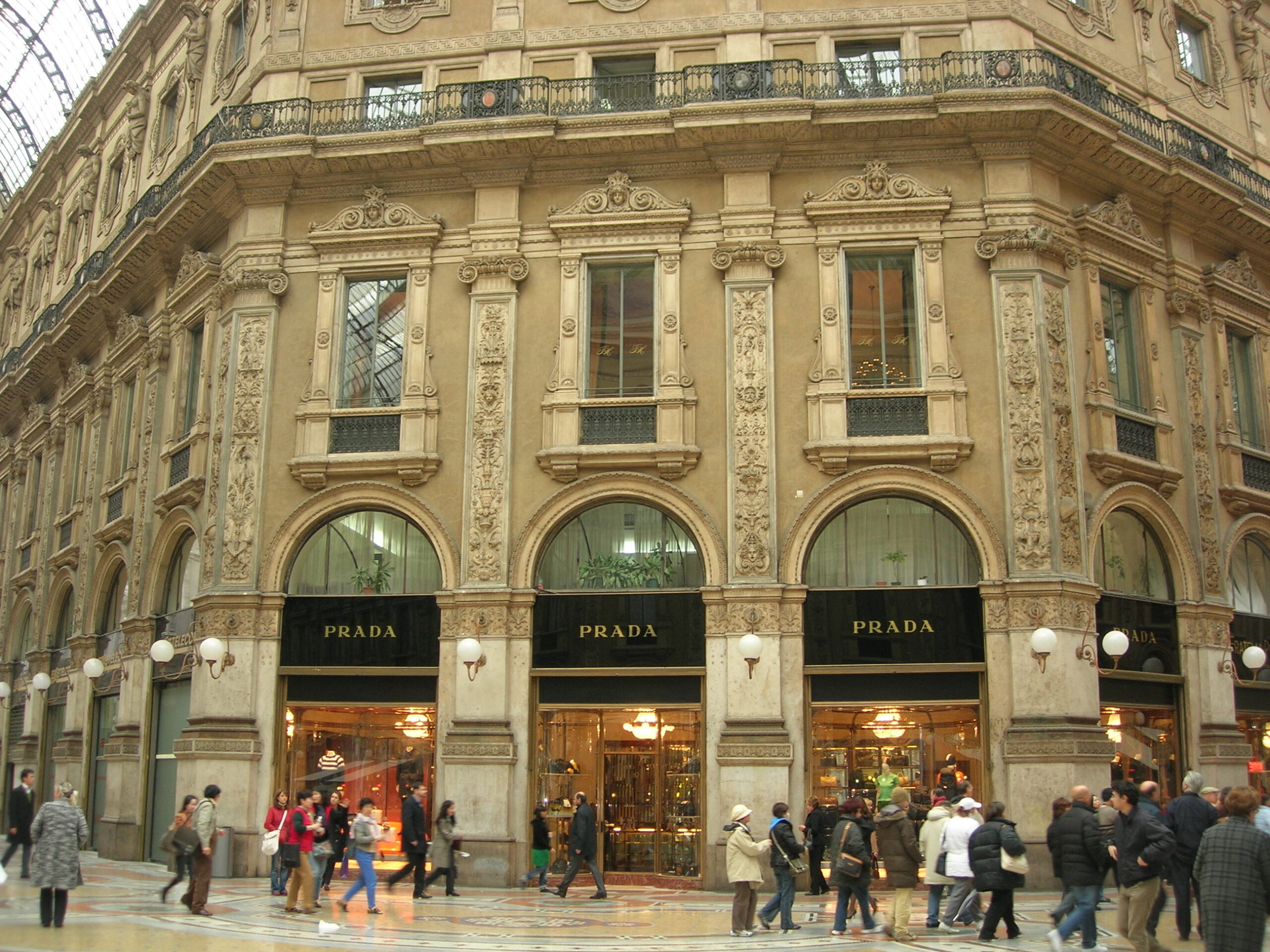 Exterior of Prada store in Galleria Vittorio Emanuele II with shoppers walking by in Milan
